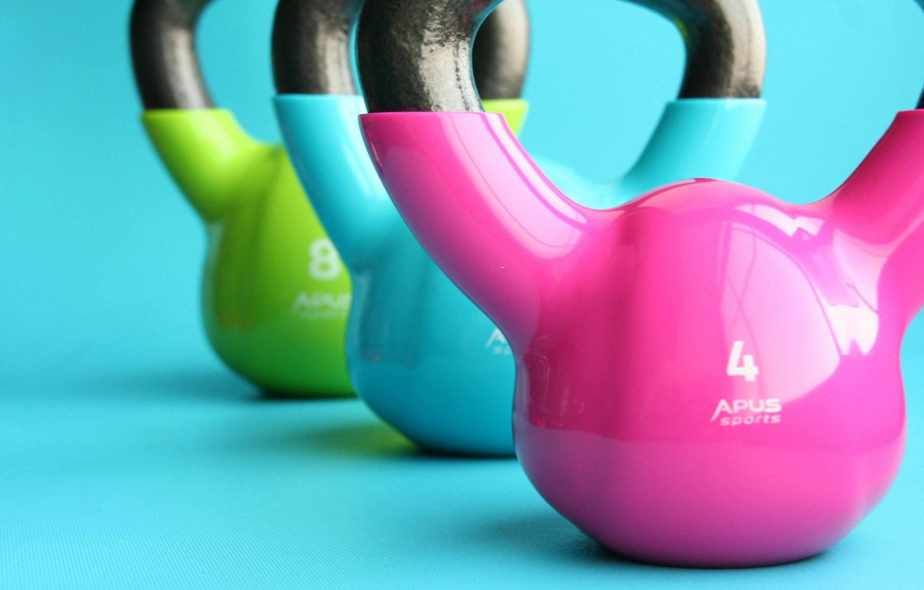 green blue and pink kettle bells on blue surface